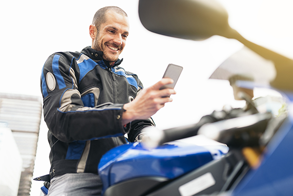 Motorcyclist looking at an iPhone, preparing to use an app.